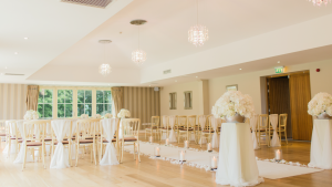 Wedding venue with hardwood floors and white linens and flowers.