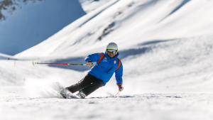 A person in blue ski gear skis down a snowy mountain. 
