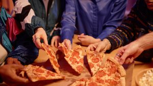 People taking slices of pizza during a party.