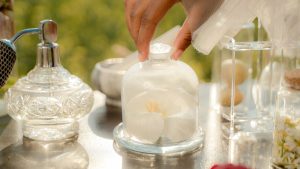 Perfume bottles, flowers, and herbs on a table.