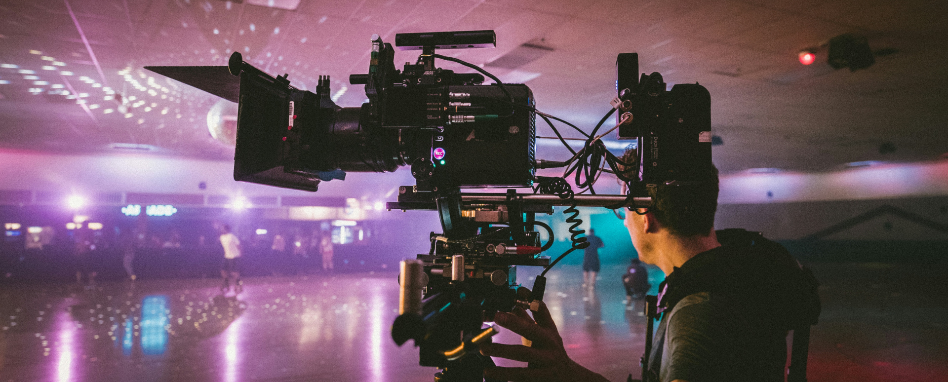 Cameraman films an indoor event taking place in a roller skating rink.