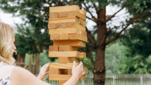 A blonde woman playing outdoor giant Jenga.