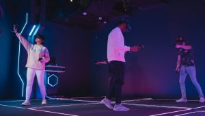 Three people on a stage with purple lighting hosting a VR dance party.