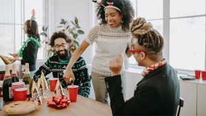 Six employees at a company holiday party holding wine glasses.