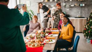 Six people sit around a table at Thanksgiving as they get their picture taken.