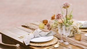 Rustic table setting with wildflowers, white plates, and decor.