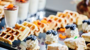 Brunch buffet with blueberry waffles, yogurt, and muffins.