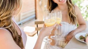 Two women toast with mimosas.