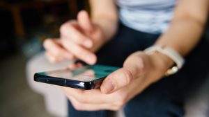 A woman scrolls through her smartphone.